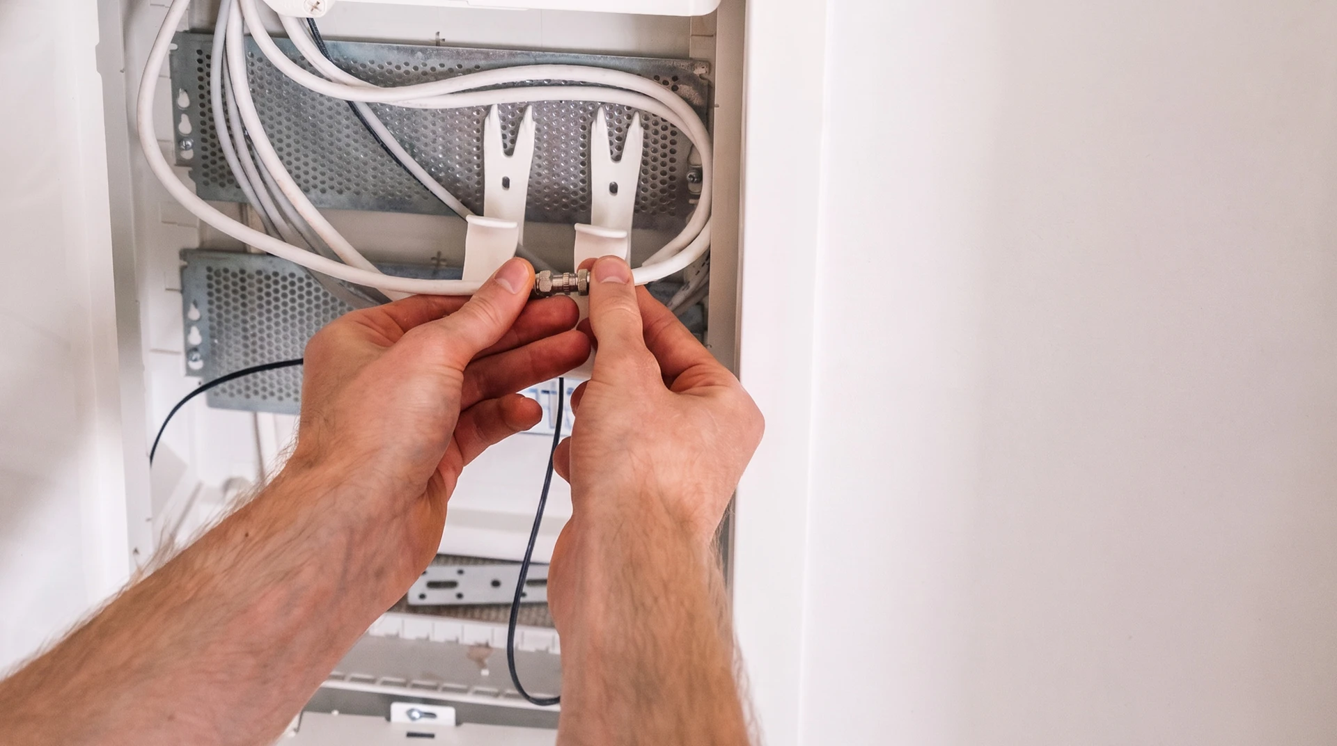 Électricien professionnel en extérieur près de son fourgon utilitaire blanc, portant casque de sécurité blanc et gants de protection