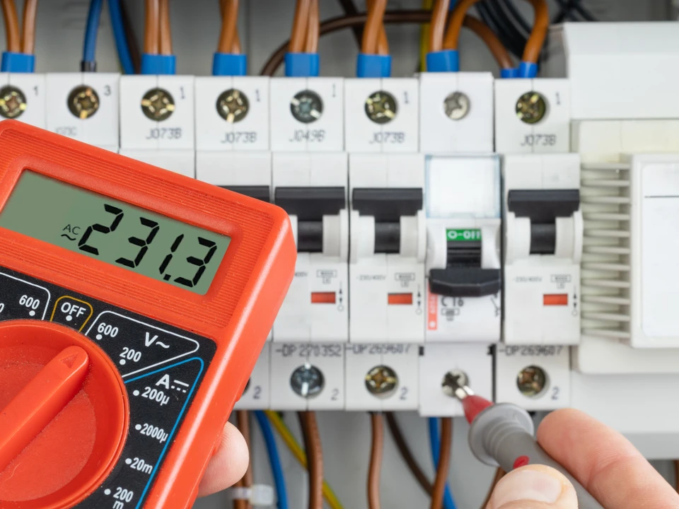 Espace de travail d'électricien avec plans techniques étalés sur table blanche